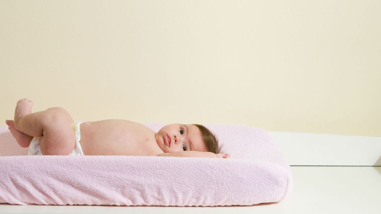 Baby on a change table with pink blanket
