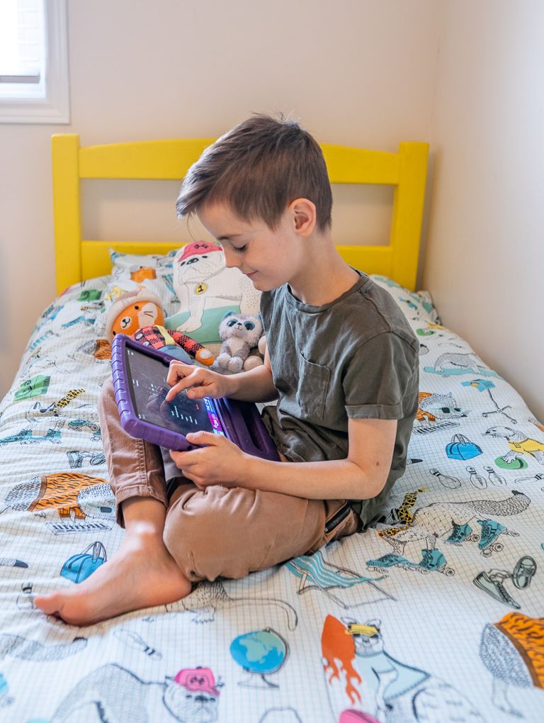 Christine's son setting an alarm on his iPad, sitting on his bed