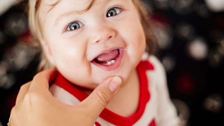 The first teeth of a child. Smile and laugh. Mom's hand.