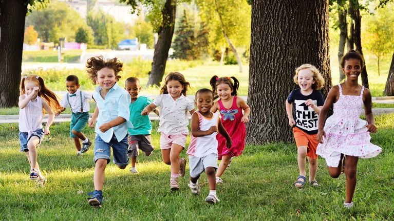 A group of happy children of boys and girls run in the Park on the grass on a Sunny summer day . 