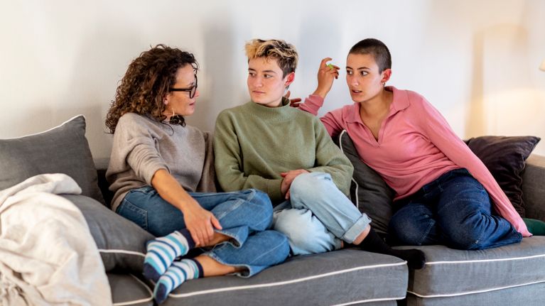 three woman are sitting together on a sofa