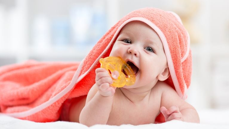 Cute baby with teether under a hooded towel after bath