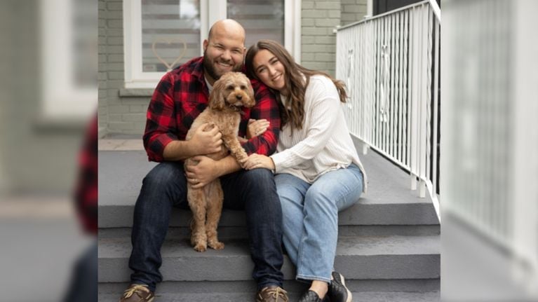 Couple and their dog sitting on the front steps of their home