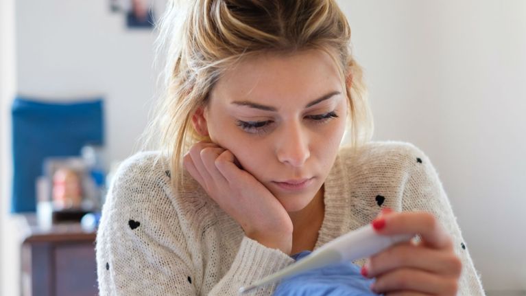 Woman looking at a faint line on pregnancy test