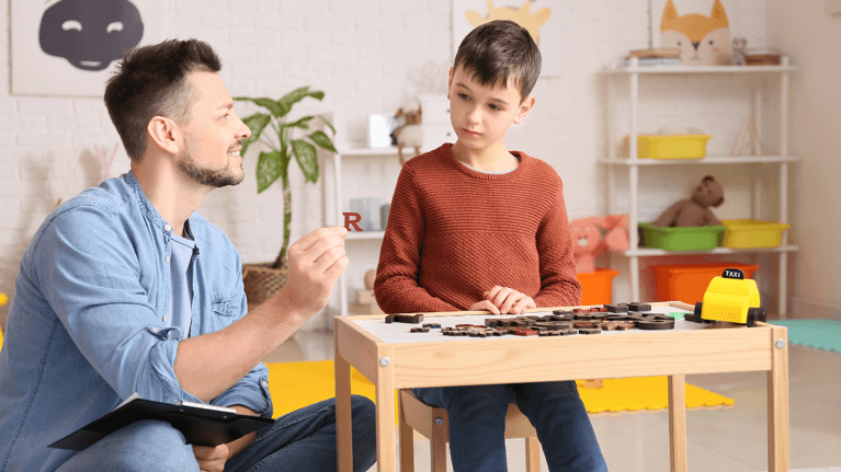 child sitting at a table with his father looking at a puzzle