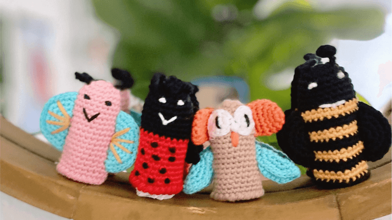 4 finger puppets sitting on display on a piece of wood