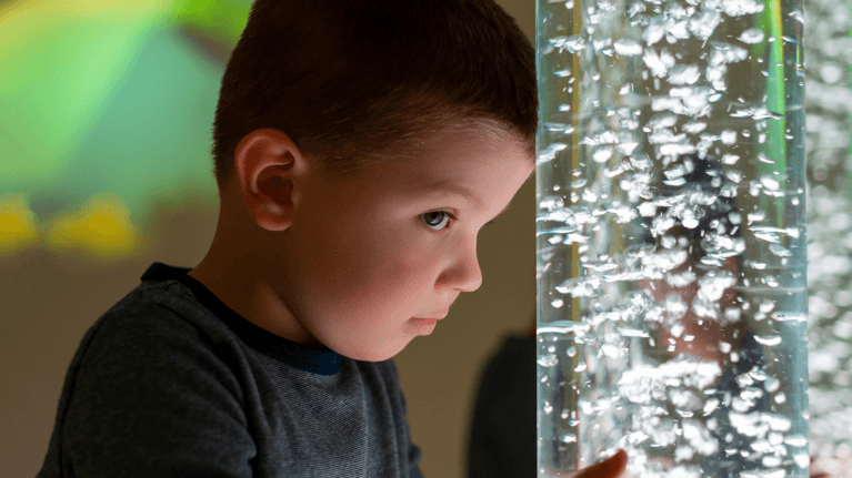child sad looking at a light up water feature
