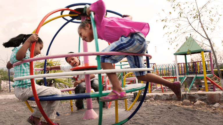 three kids playing at a park playground